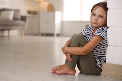 Photo of Orphanage concept. Sad girl sitting on floor indoors