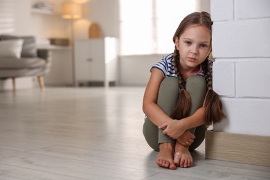 Photo of Orphanage concept. Sad girl sitting on floor indoors