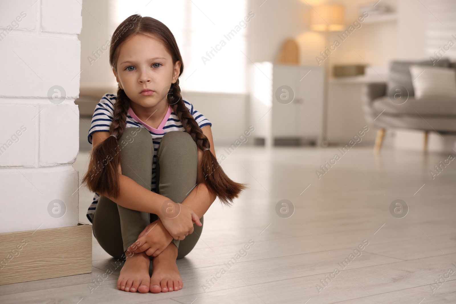 Photo of Orphanage concept. Sad girl sitting on floor indoors