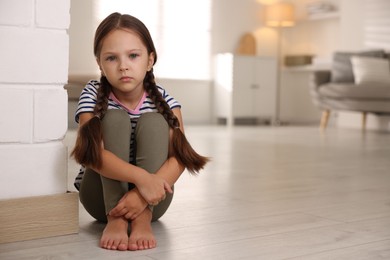 Photo of Orphanage concept. Sad girl sitting on floor indoors