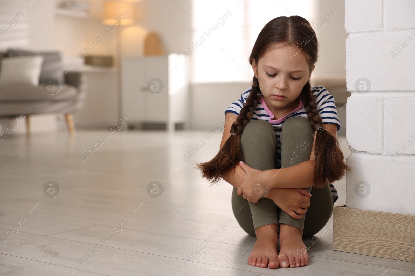 Photo of Orphanage concept. Sad girl sitting on floor indoors