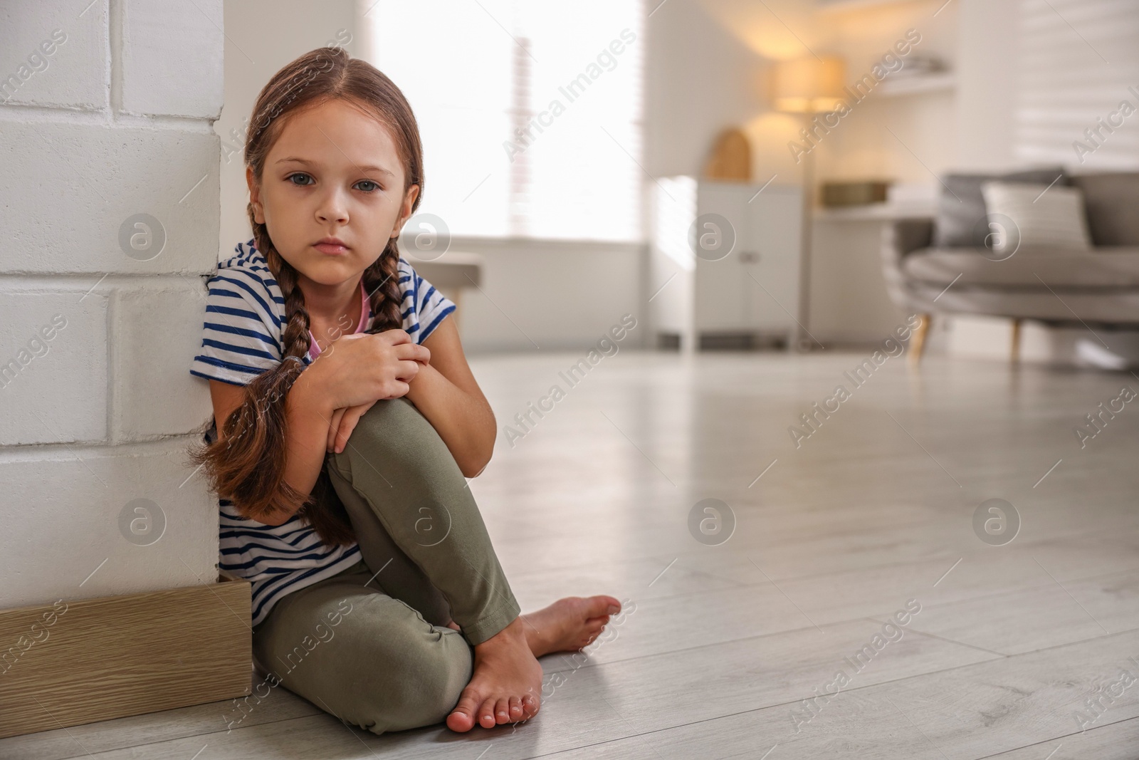 Photo of Orphanage concept. Sad girl sitting on floor indoors