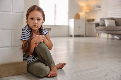 Orphanage concept. Sad girl sitting on floor indoors