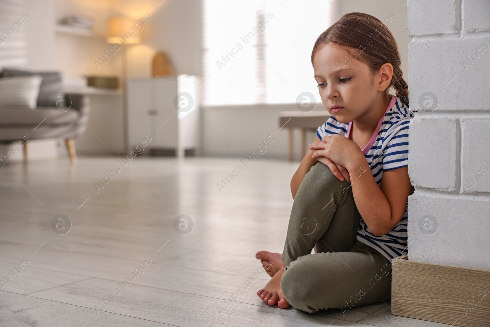 Photo of Orphanage concept. Sad girl sitting on floor indoors