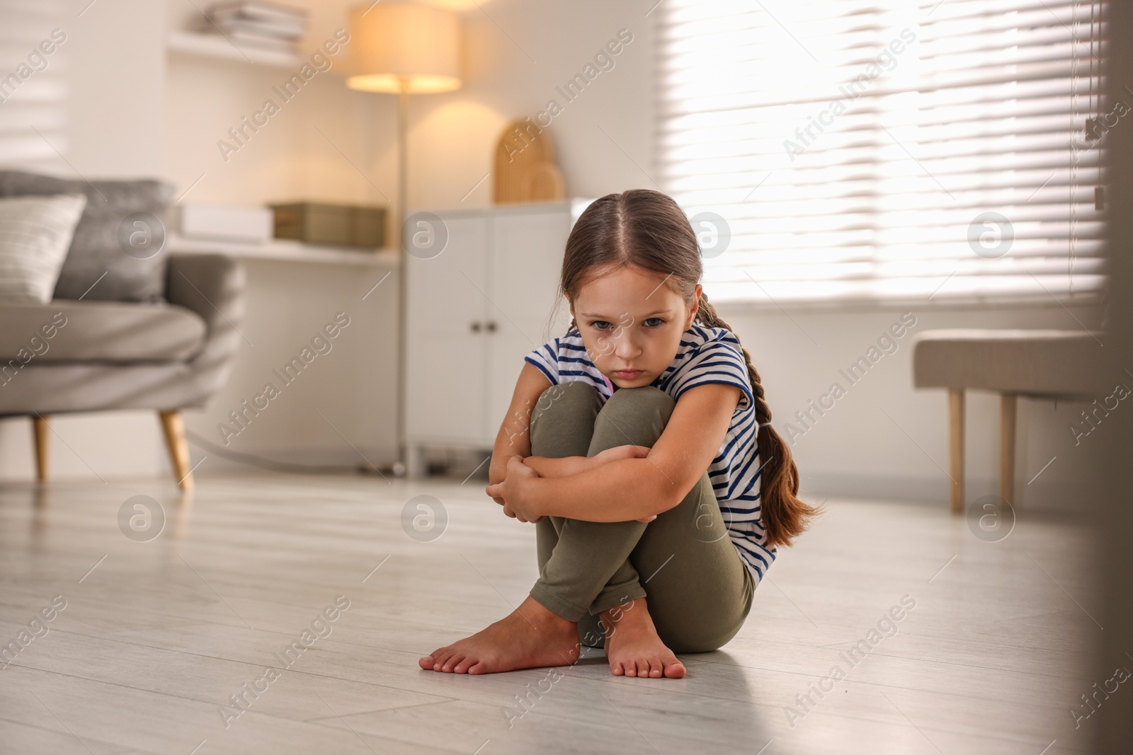 Photo of Orphanage concept. Sad girl sitting on floor indoors