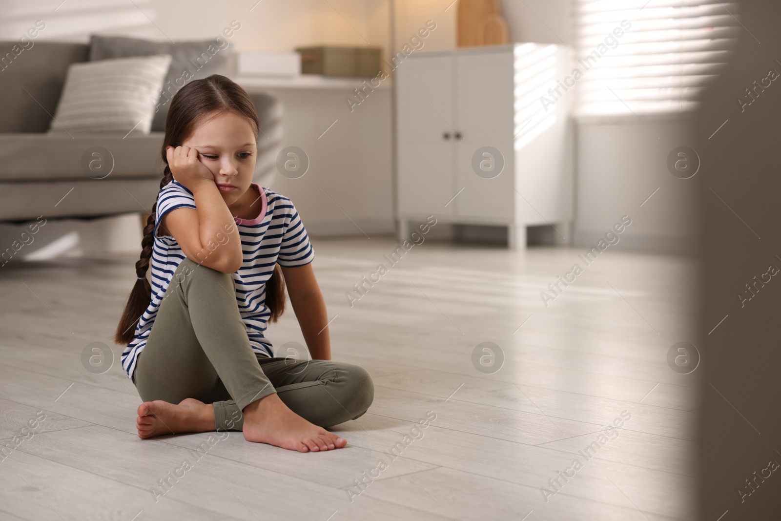 Photo of Orphanage concept. Sad girl sitting on floor indoors