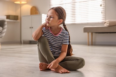 Orphanage concept. Sad girl sitting on floor indoors