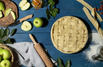 Photo of Uncooked homemade apple pie and ingredients on blue wooden table, flat lay