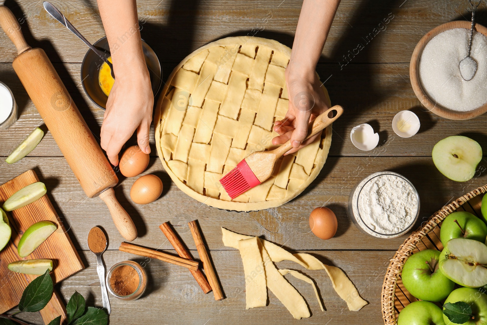 Photo of Woman making homemade apple pie and ingredients on wooden table, top view