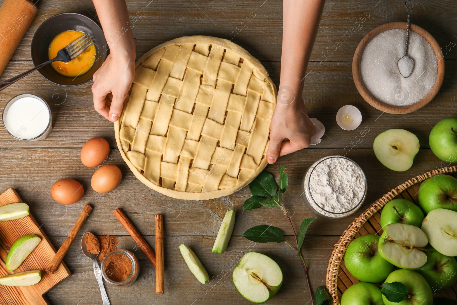 Photo of Woman making homemade apple pie and ingredients on wooden table, top view