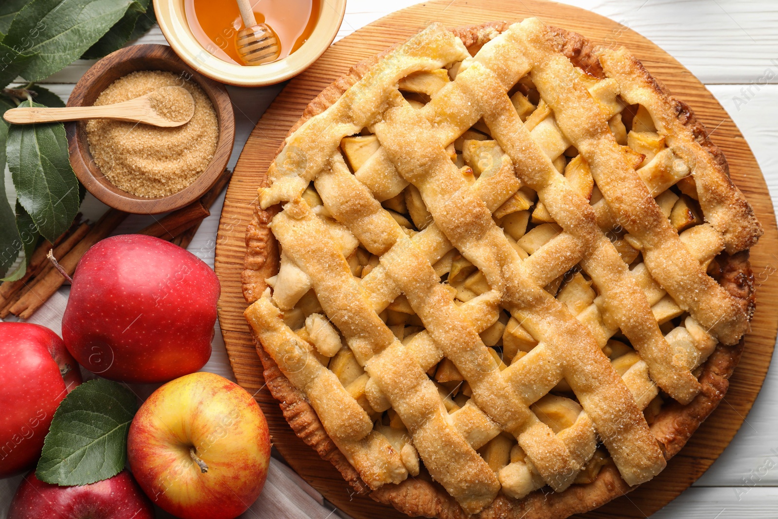 Photo of Tasty homemade apple pie and ingredients on white wooden table, flat lay