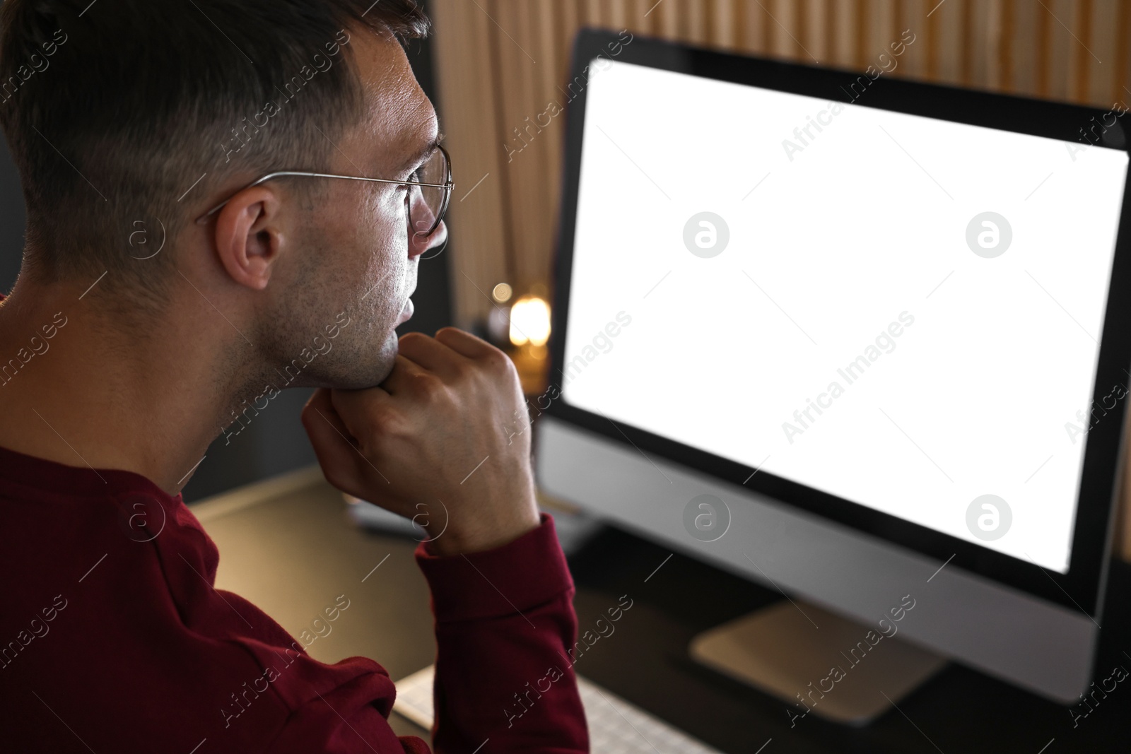 Photo of Man using computer monitor at table indoors