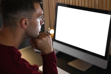 Photo of Man using computer monitor at table indoors