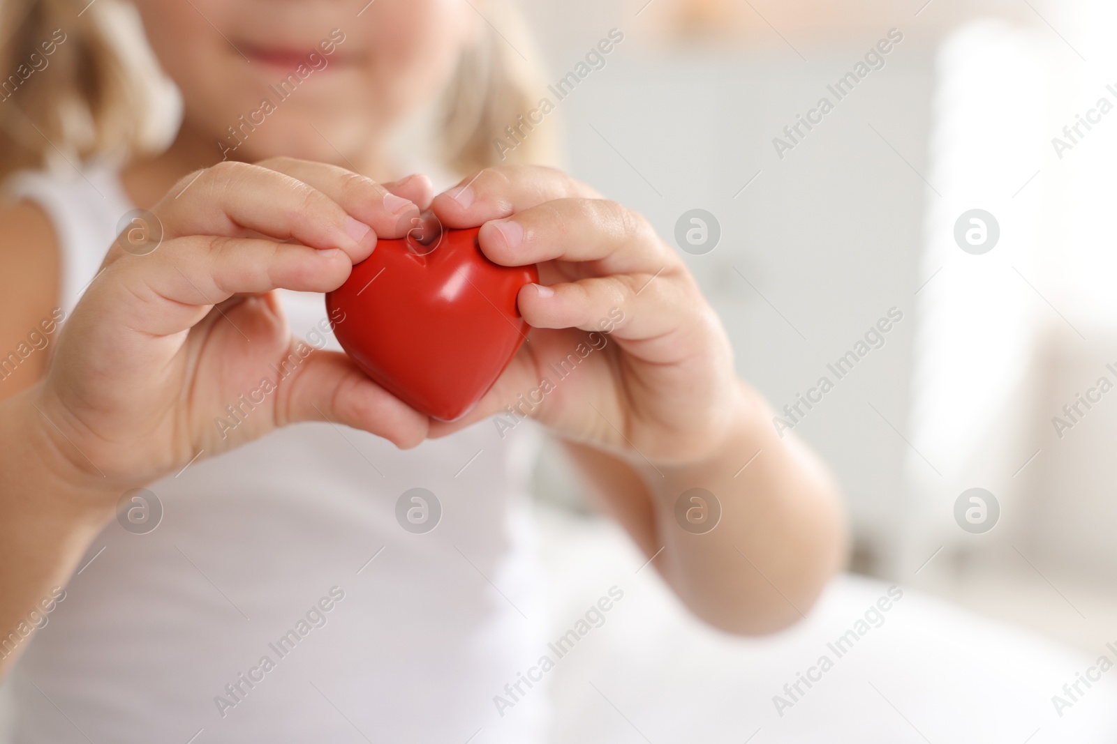 Photo of Orphanage concept. Little girl with red heart figure indoors, closeup