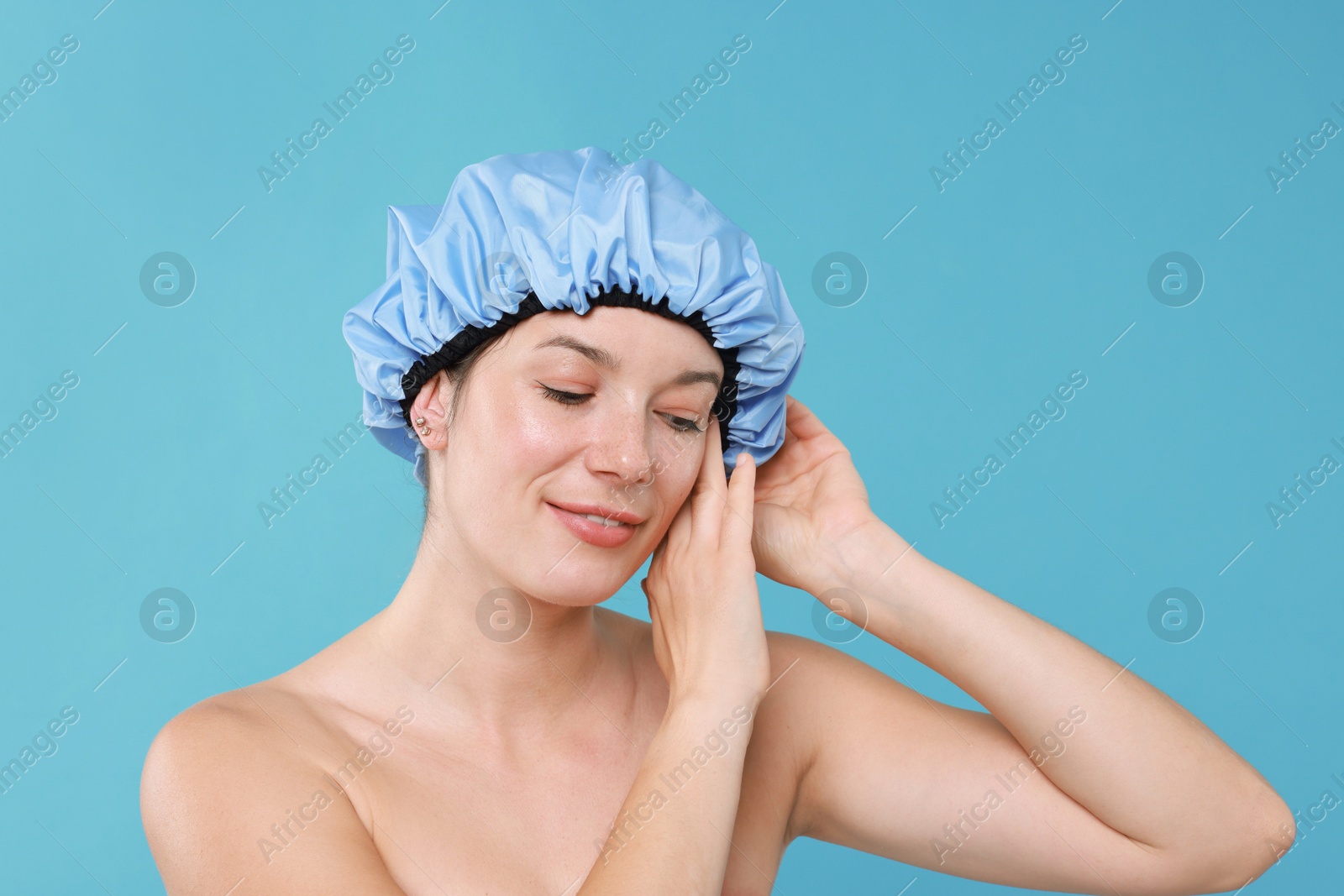 Photo of Woman wearing shower cap on light blue background