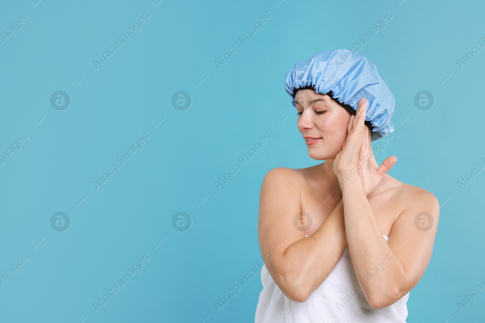 Photo of Woman wearing shower cap on light blue background, space for text