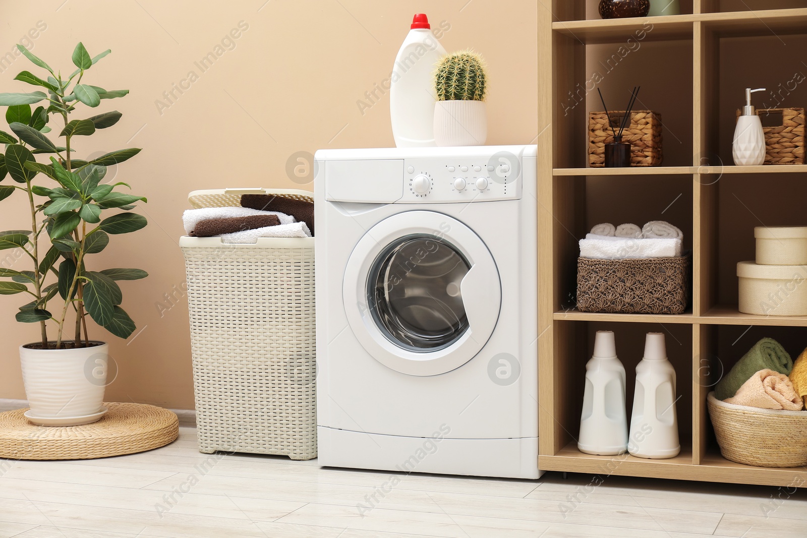 Photo of Wicker basket full of laundry, washing machine and detergent in bathroom