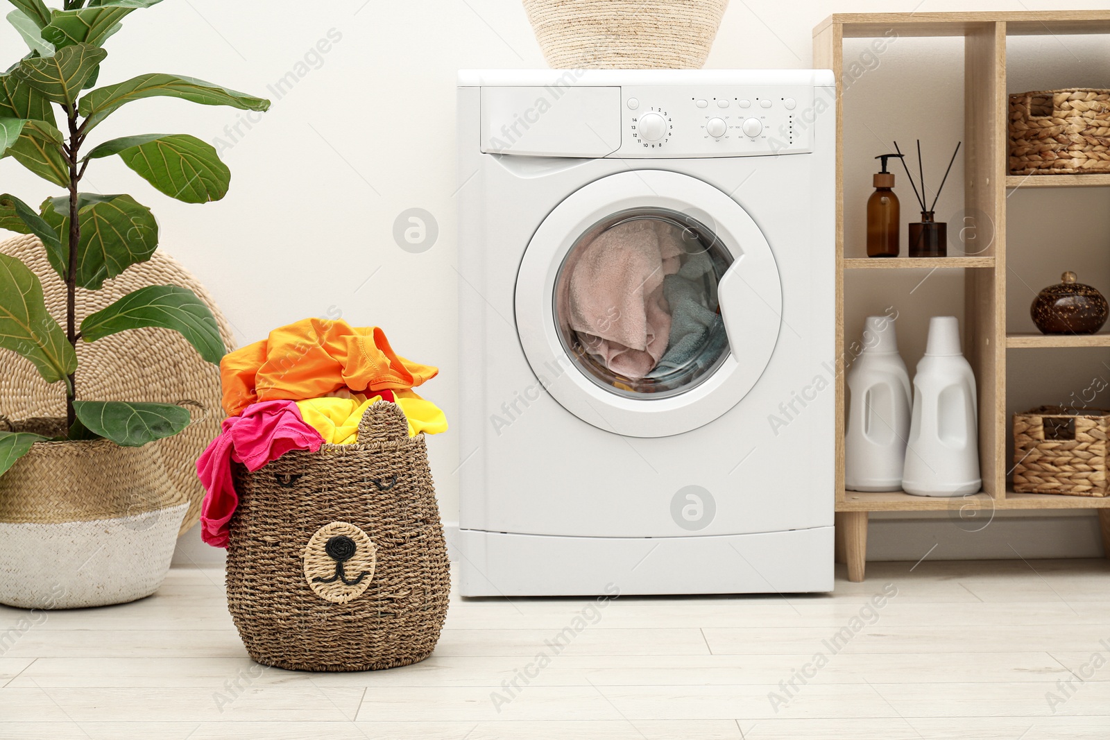 Photo of Wicker basket full of laundry near washing machine in bathroom