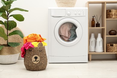 Photo of Wicker basket full of laundry near washing machine in bathroom