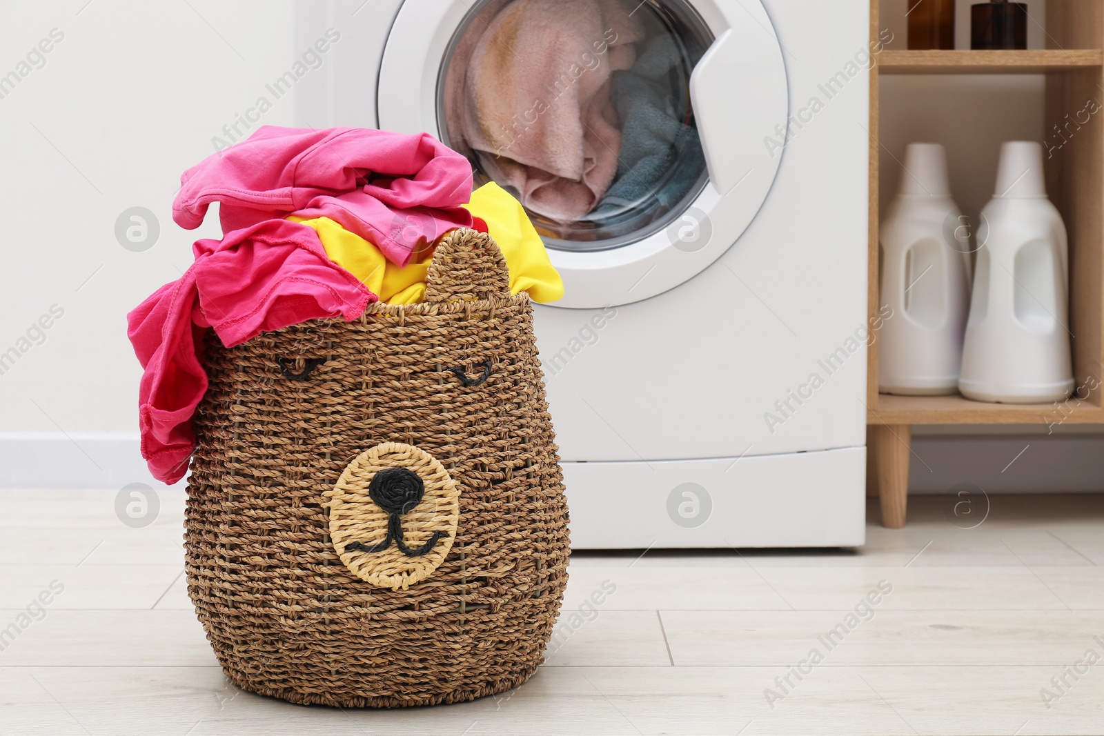 Photo of Wicker basket full of laundry near washing machine in bathroom