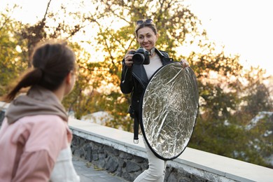 Professional photographers with reflector and camera outdoors