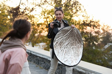 Professional photographers with reflector and camera outdoors