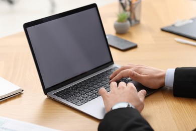 Photo of Businessman working with laptop at wooden table in office, closeup