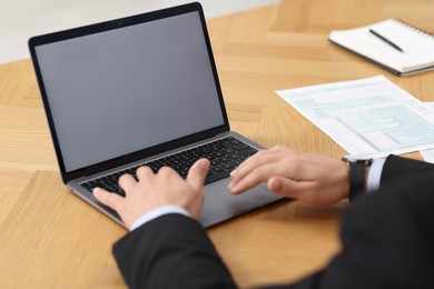 Photo of Businessman working with laptop at wooden table in office, closeup