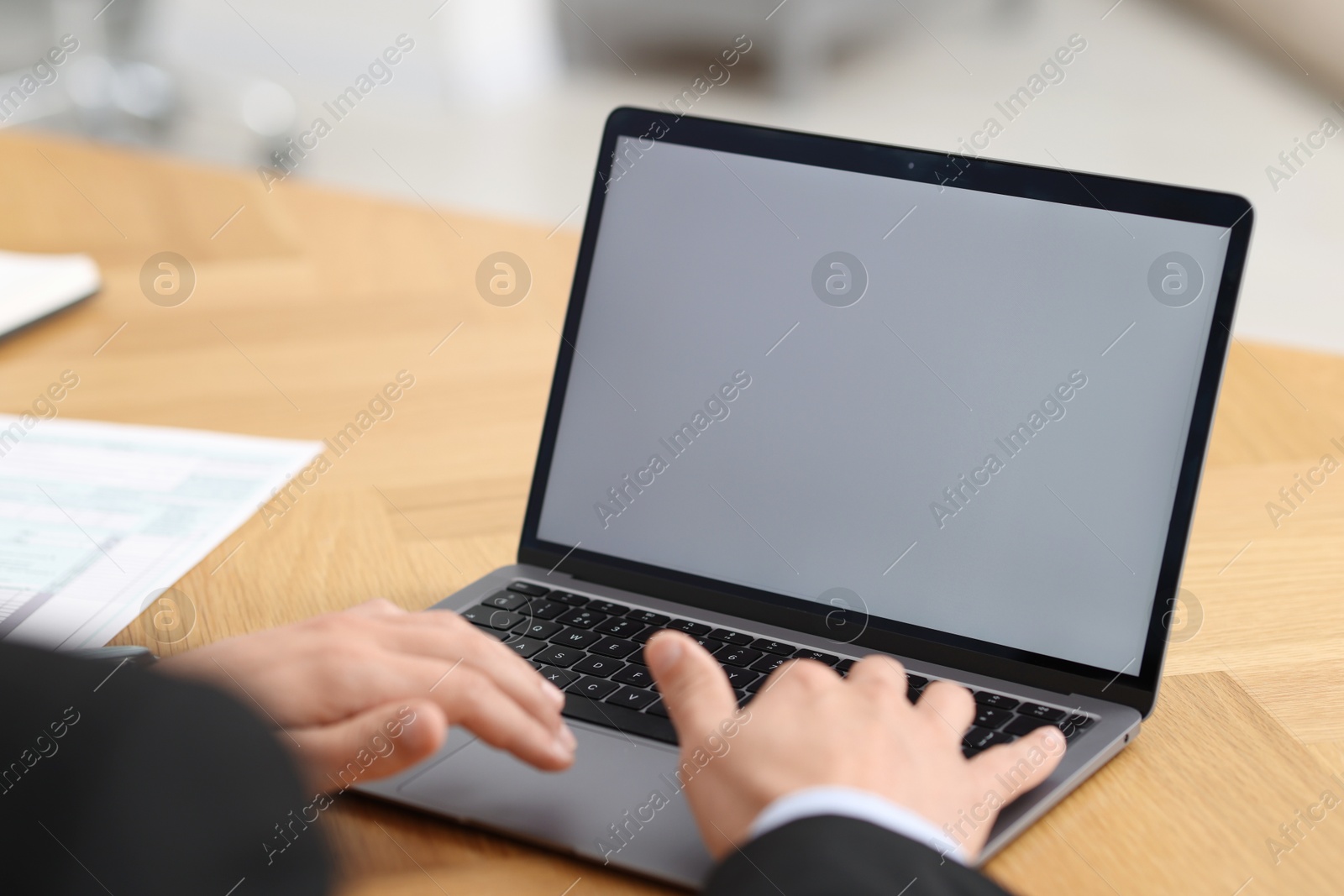 Photo of Businessman working with laptop at wooden table in office, closeup