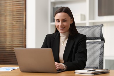 Photo of Businesswoman working with laptop at table in office