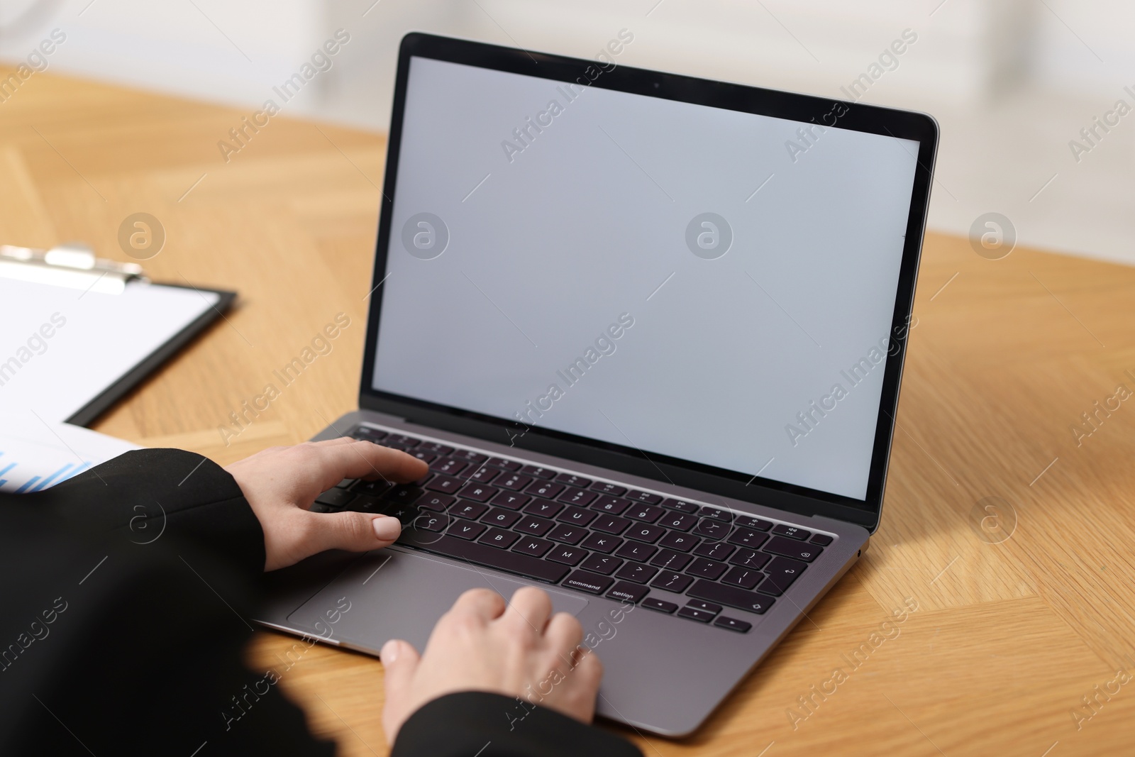 Photo of Businesswoman working with laptop at wooden table in office, closeup