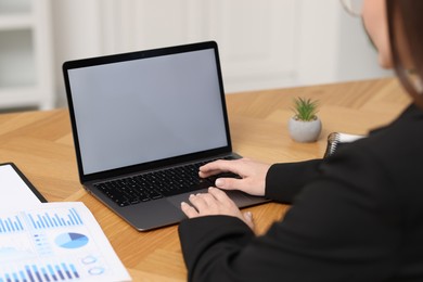 Photo of Businesswoman working with laptop at wooden table in office, closeup