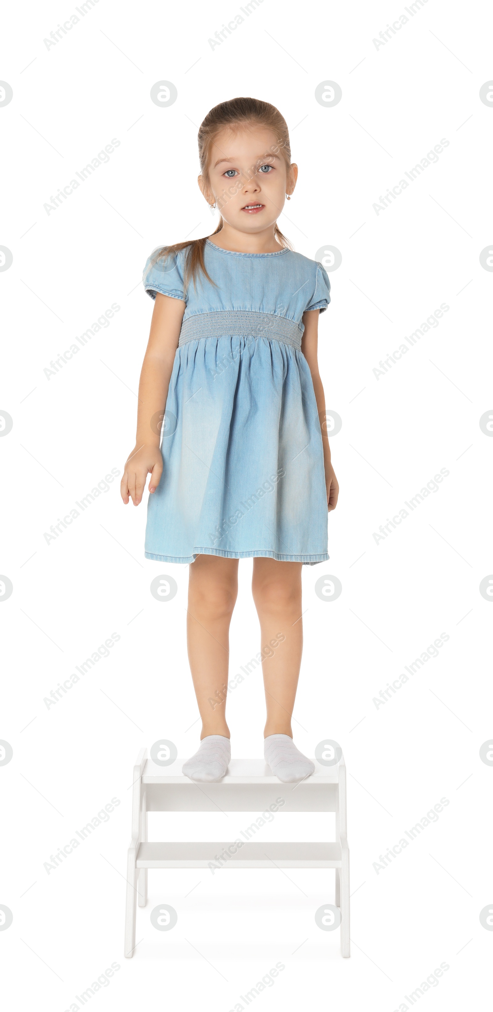 Photo of Little girl standing on step stool against white background