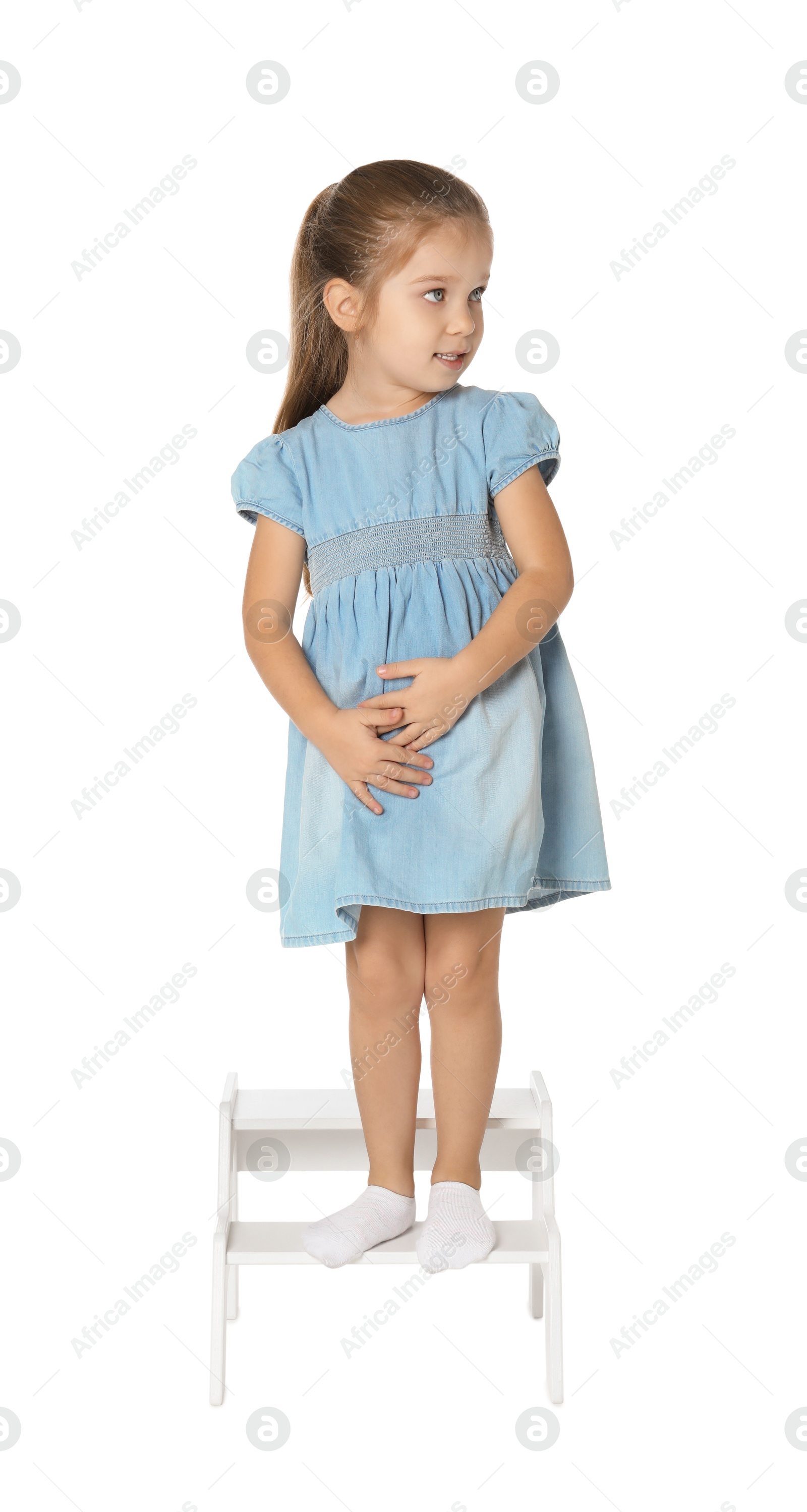 Photo of Little girl standing on step stool against white background