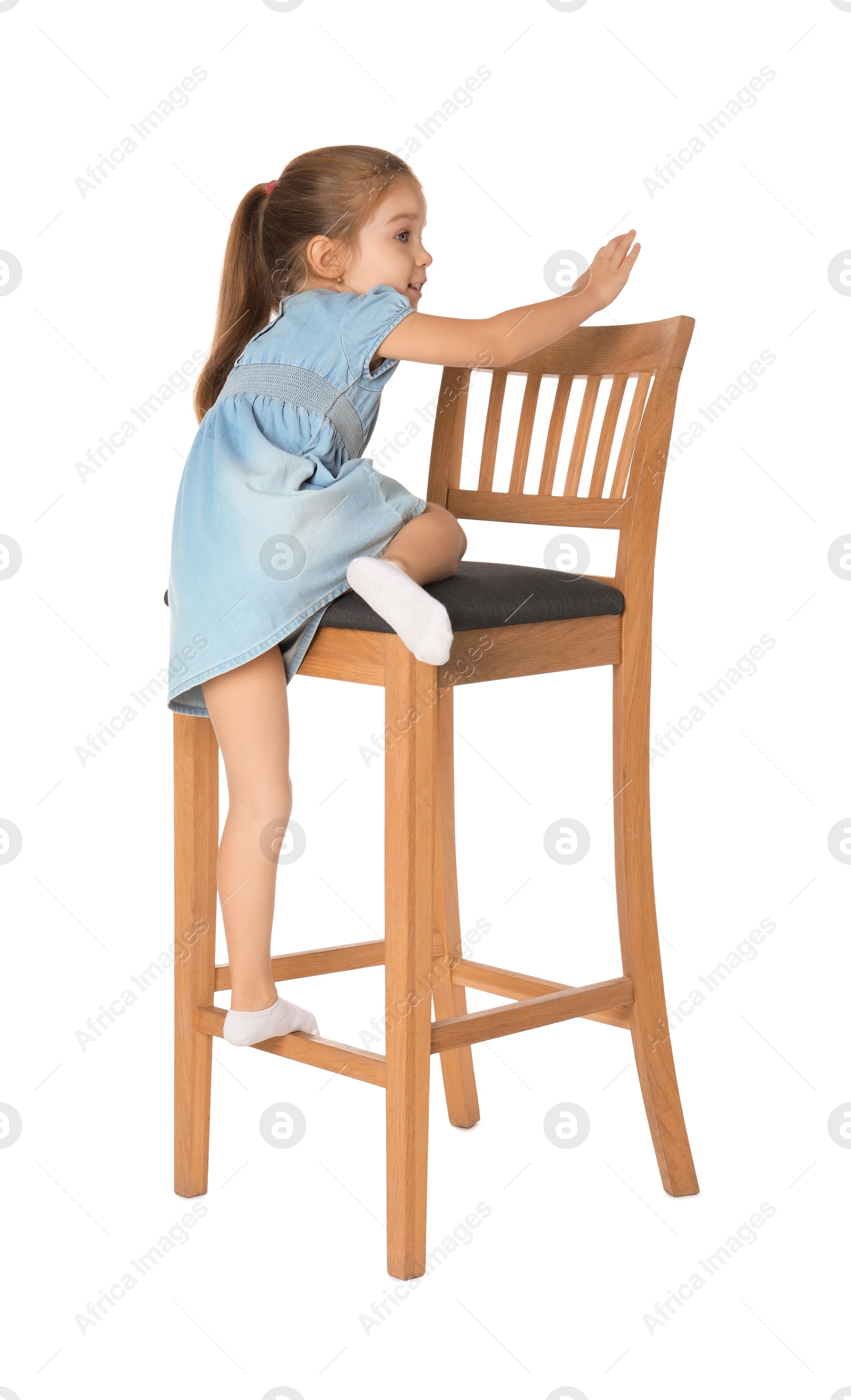 Photo of Little girl standing on stool against white background