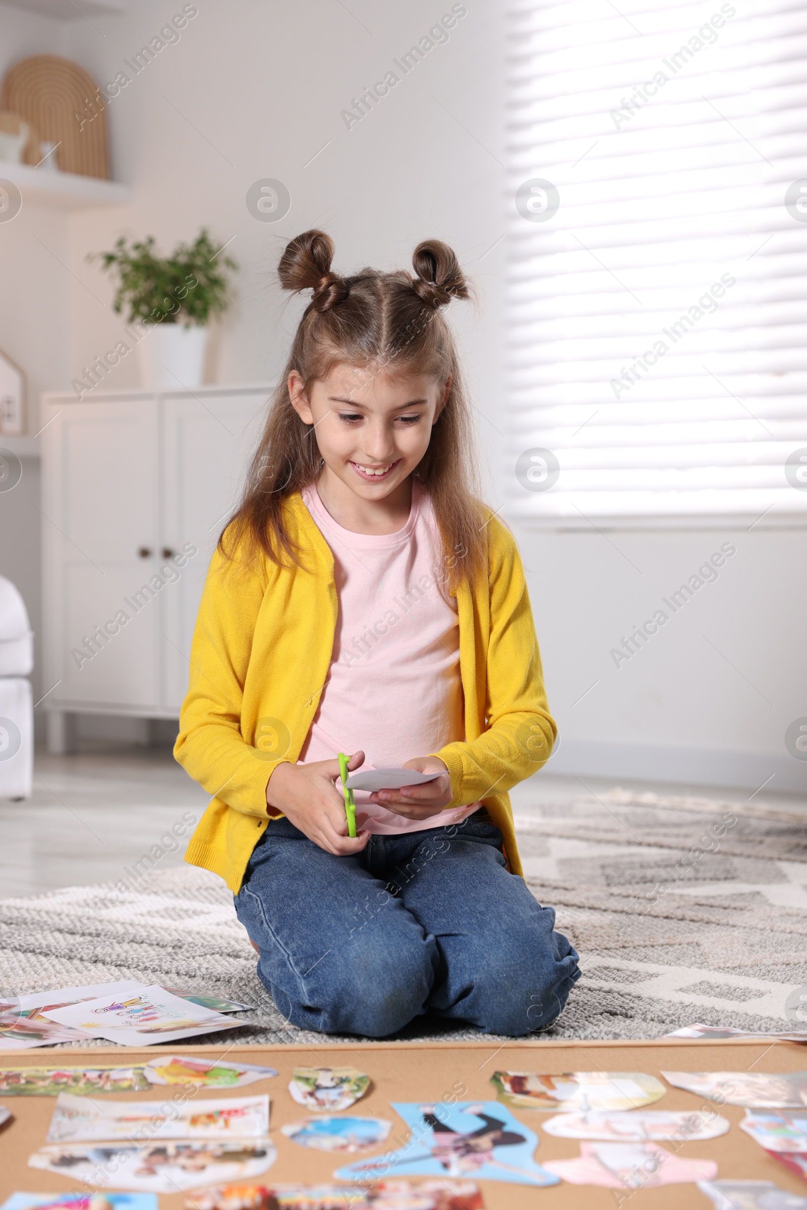 Photo of Creating vision board. Girl cutting out picture on floor indoors