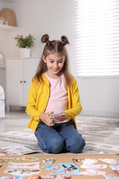 Photo of Creating vision board. Girl cutting out picture on floor indoors