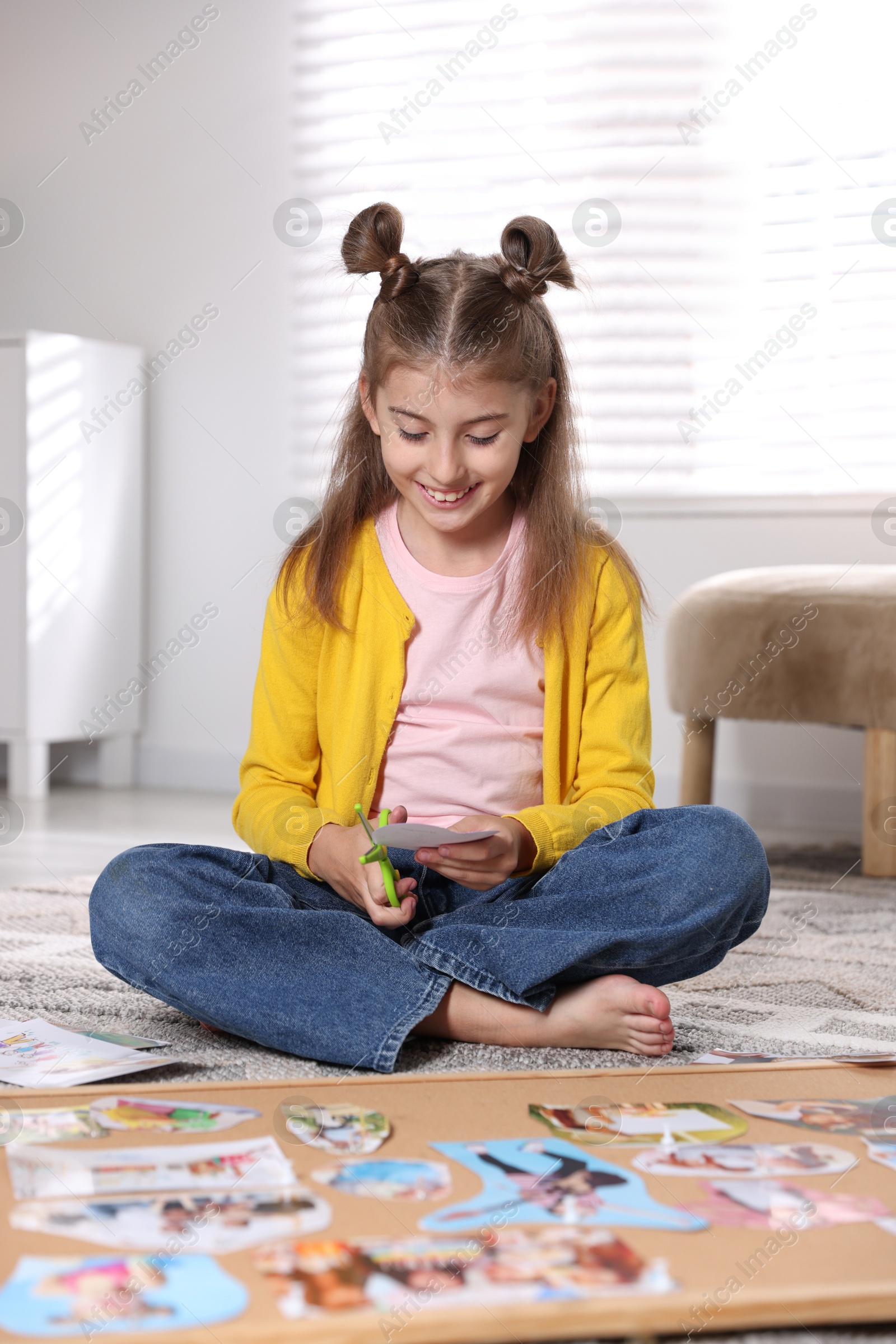 Photo of Creating vision board. Girl cutting out picture on floor indoors