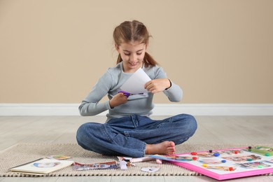 Photo of Creating vision board. Girl cutting out picture on floor indoors