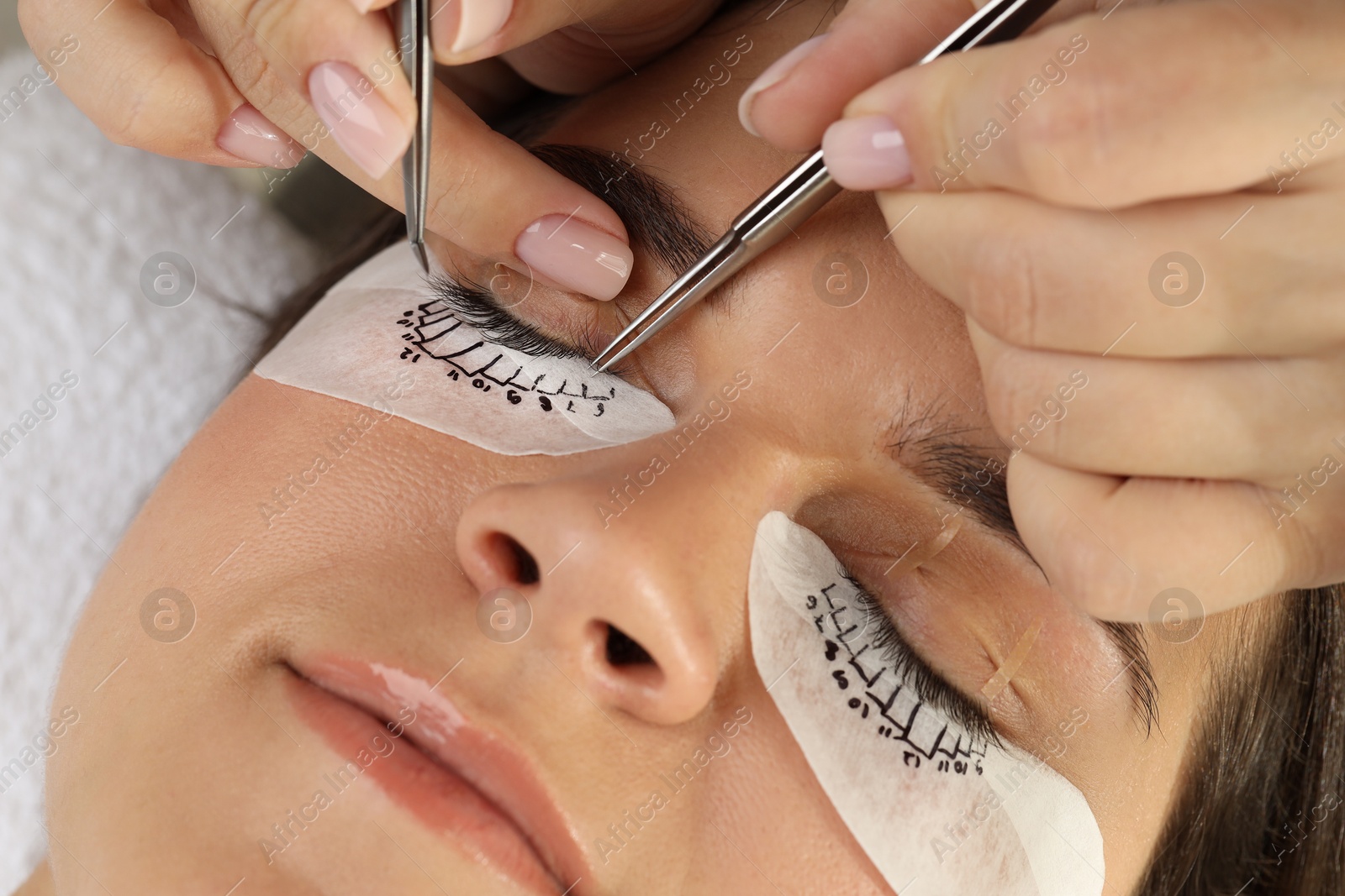 Photo of Woman undergoing lash extensions procedure in beauty salon, closeup