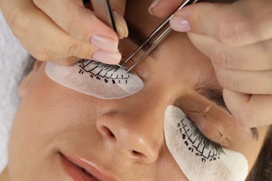 Woman undergoing lash extensions procedure in beauty salon, closeup