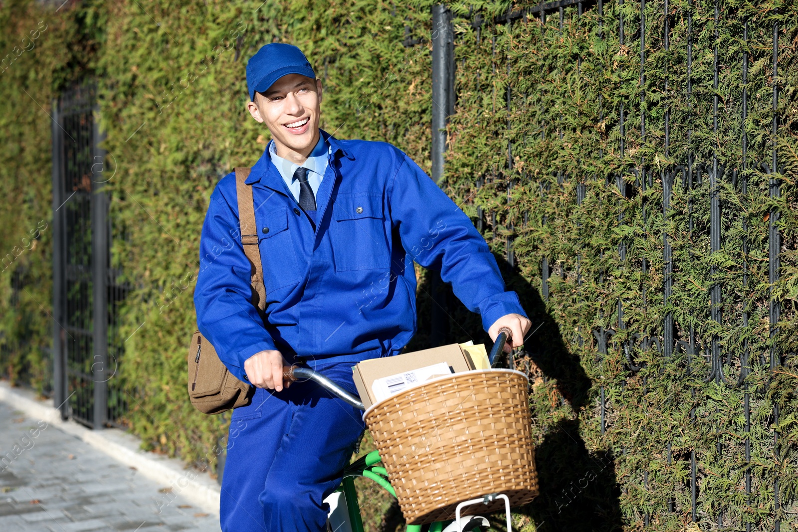 Photo of Postman with parcels in bicycle basket outdoors