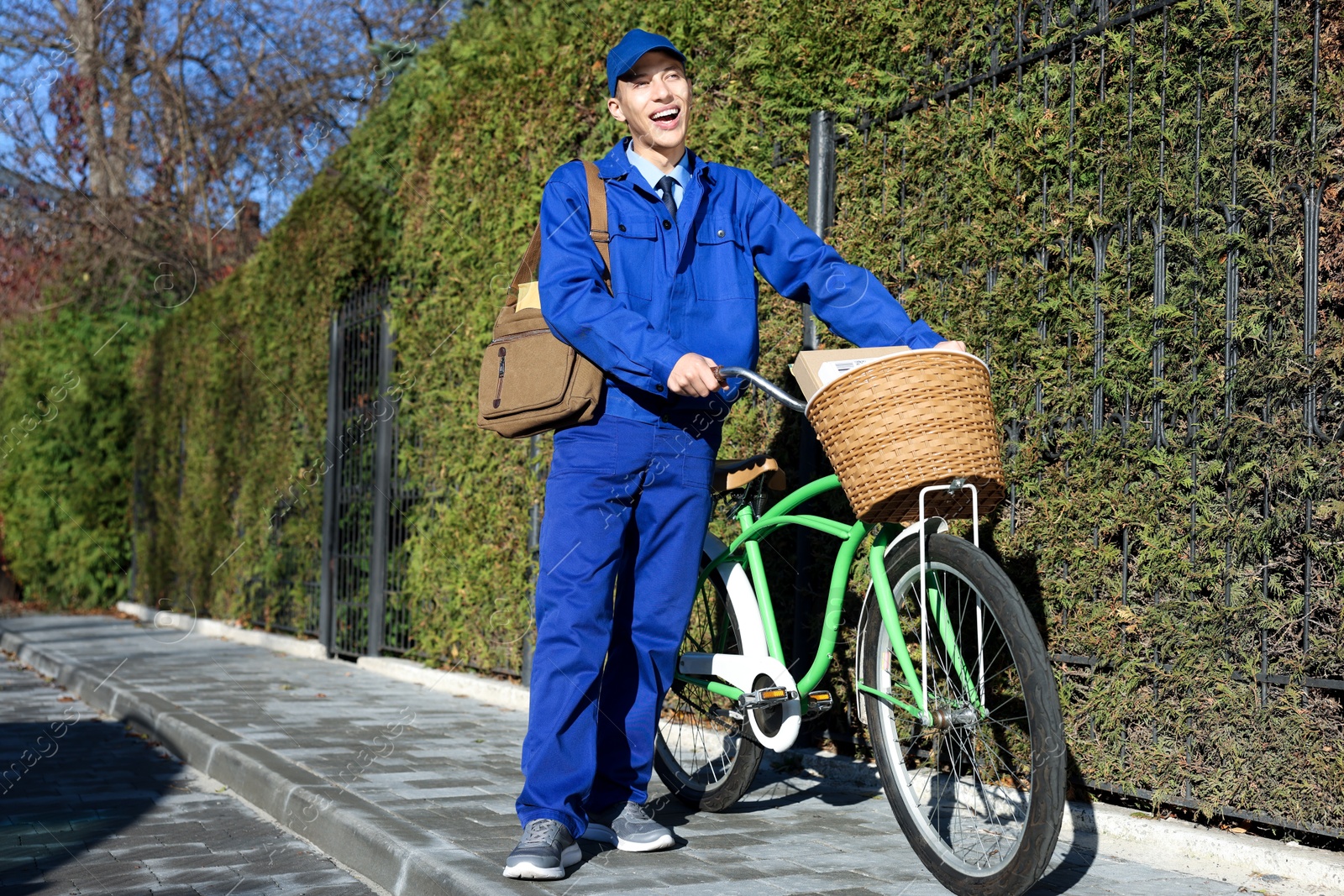 Photo of Postman with parcels in bicycle basket outdoors