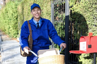 Photo of Postman with parcels in bicycle basket outdoors