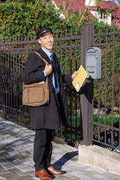 Happy postman with parcel outdoors. Mail service