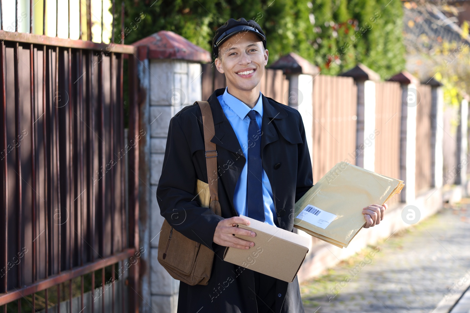 Photo of Happy postman with parcels outdoors. Mail service