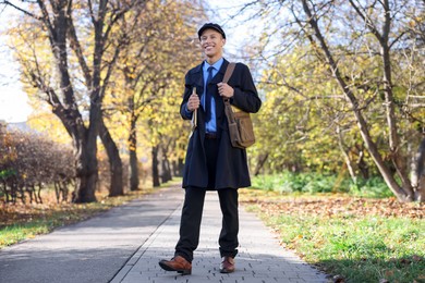 Photo of Happy postman with bag and envelopes outdoors