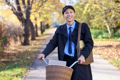 Happy mailman with bicycle outdoors. Postal service