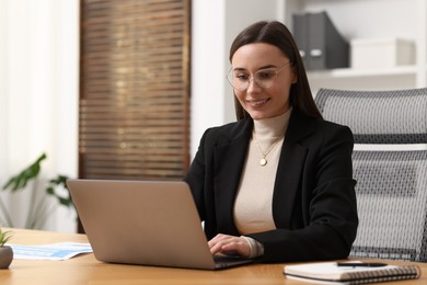 Photo of Businesswoman working with laptop at table in office