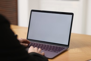 Photo of Businesswoman working with laptop at wooden table in office, closeup